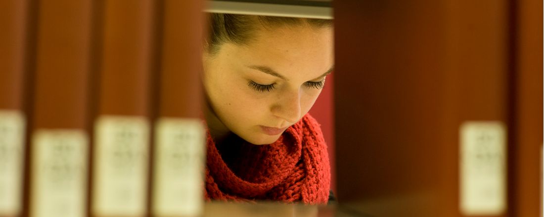 Studentin der Uni Bayreuth liest ein Buch in der Bibliothek.