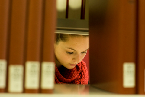Studentin der Uni Bayreuth liest ein Buch in der Bibliothek.